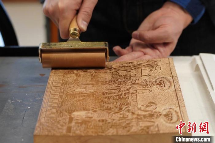 圖為徐晉林工作室工作人員正在給雕好壁畫的版面滾油墨?！【琶赖┰?　攝