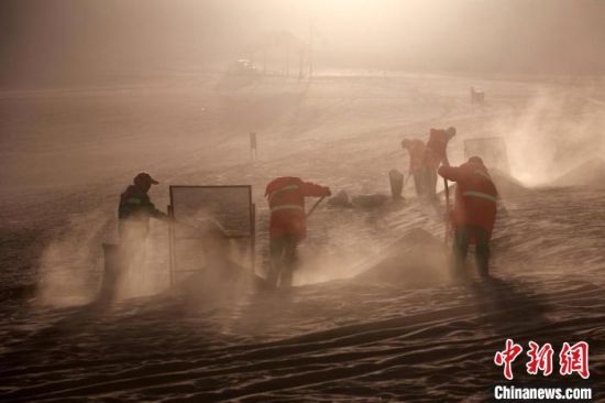 圖為敦煌市鳴沙山月牙泉景區(qū)“駱駝保姆”清理駱駝糞便。　張曉亮 攝