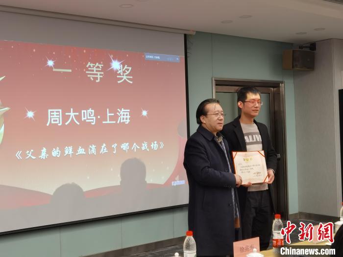 圖為作家、西北師范大學(xué)新聞與傳媒學(xué)院院長(zhǎng)徐兆壽頒發(fā)一等獎(jiǎng)證書(shū)，代領(lǐng)獎(jiǎng)?wù)呱吓_(tái)領(lǐng)獎(jiǎng)?！钅?攝