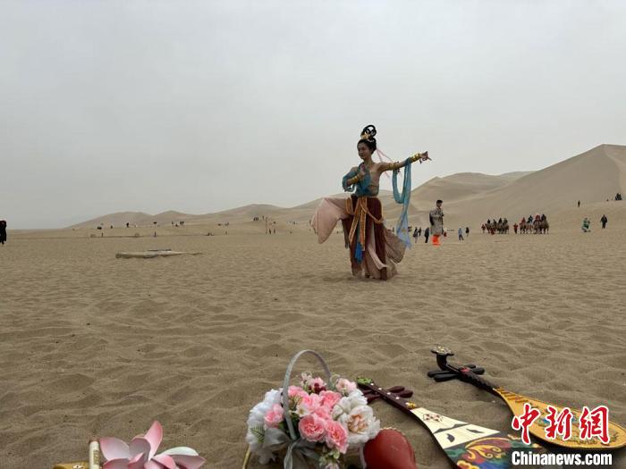 圖為2023年4月底，敦煌大漠“逐舞者”奧楠在鳴沙山月牙泉景區(qū)視頻直播敦煌舞?！●T志軍 攝