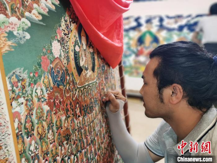 圖為更登才讓的徒弟繪畫唐卡?！?zhí)砀?攝
