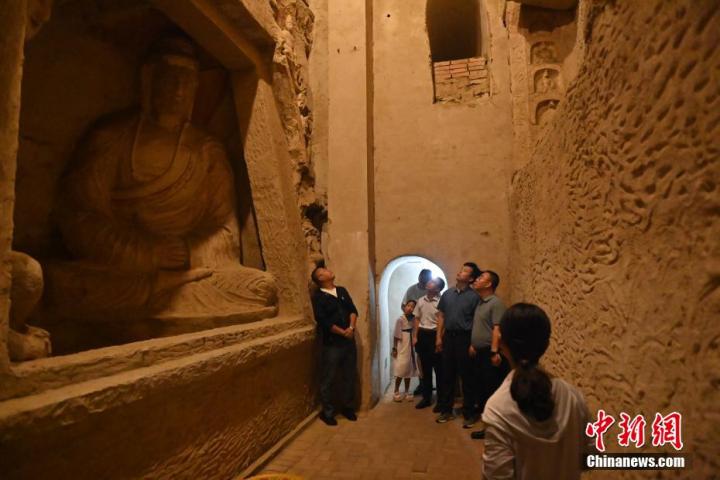 7月15日，游人參觀甘肅省平涼市涇川縣百里石窟長廊中的王母宮石窟。百里石窟長廊位于涇川縣境內，由512個石窟、5眼窟中石井組成，現(xiàn)存王母宮石窟、鳳凰山石窟、南石窟寺、丈八寺石窟、羅漢洞石窟、太山寺石窟等規(guī)模較大的石窟群，還有數(shù)量眾多的小石窟群。王母宮石窟又名千佛洞，該窟設計宏大，造像生動，窟內擁有造像數(shù)百尊，是較為珍貴的佛教文化歷史遺存。中新社記者 李亞龍 攝</p>
<p>